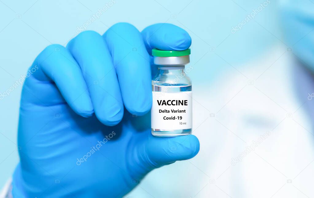 A doctor in medical gloves and a protective mask holds a bottle with coronavirus Covid19 Delta variant strain vaccine.The concept of medicine, healthcare and science.Coronavirus vaccine