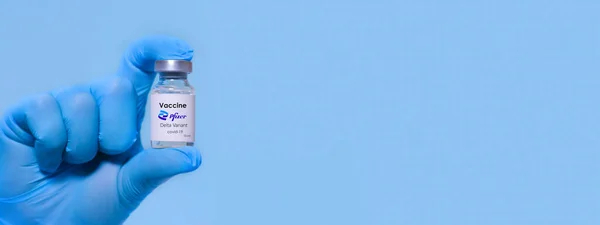 ハルキウ ウクライナだ 2020年11月23日 ラテックス手袋を着用した医師やロボラントの手は 青色の背景にファイザーを開発デルタバリアントコロナウイルスワクチンを保持しています バナー — ストック写真