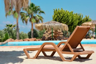 Havuzun arka planına, palmiye ağaçlarına, tropikal manzaraya karşı iskemle. Tropikal doğa, güzel manzara. Tatil ve tatil kavramı..