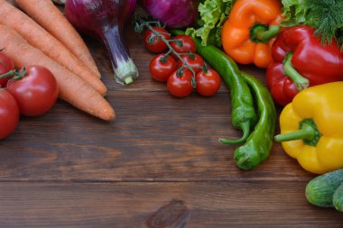 Ahşap arka planda bir sebze seti: havuç, patates, kabak, kırmızı biber, salatalık, sarımsak, domates, marul. Üst görünüm. Boşluğu kopyala