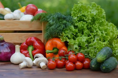 Tahta bir kutuda taze organik sebzeler ve sebze bahçesinin arka planındaki ahşap bir masada. Biyolojik, biyolojik ürünler, biyolojik ekoloji, bahçıvanlık, sağlıklı gıda, vejetaryenlik kavramı..