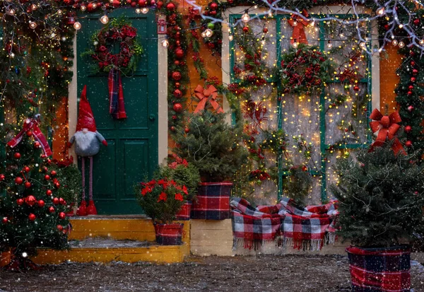 Christmas porch decorated with glowing garlands, Christmas decorations, Christmas wreath on the door, gnome, Christmas trees with decorations. Decorations for Christmas and New year.