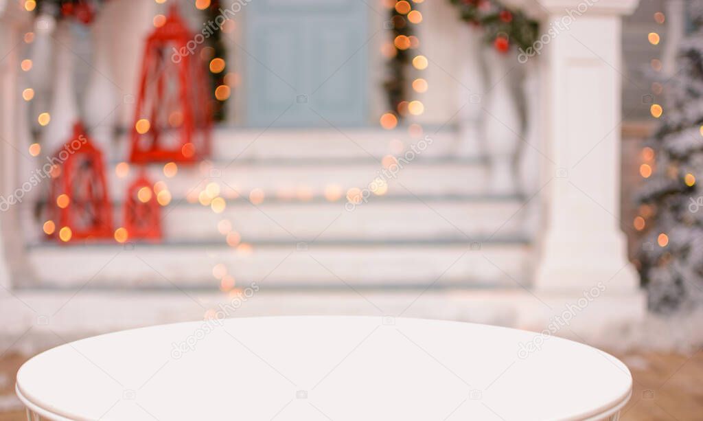 Christmas background. Empty white table on the background of a christmas porch with red lights and New Year's bokeh .Ready for product montage