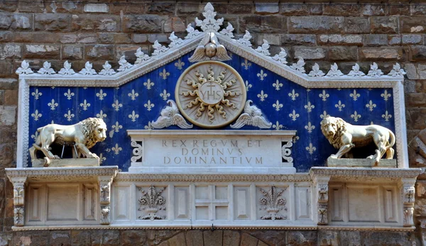 Medailon s monogramem Krista mezi dvěma lvy nad The Palazzo Vecchio je radnice ve Florencii, Itálie. — Stock fotografie