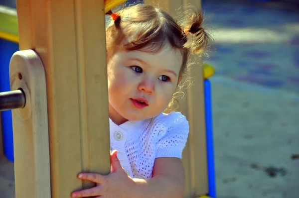 Linda menina olha para o parque infantil — Fotografia de Stock