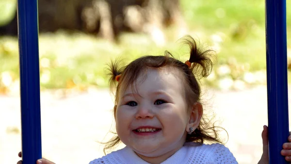 Счастливая девушка катается на качелях на детской площадке — стоковое фото