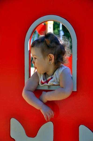 Chica está espiando por la ventana en el patio de recreo — Foto de Stock