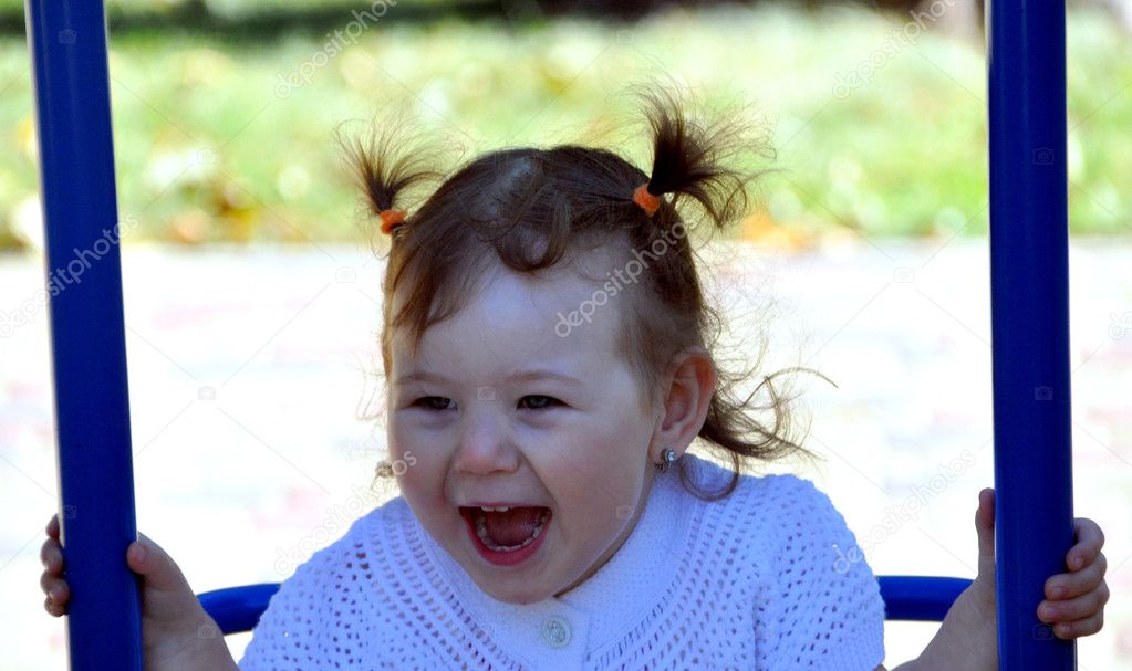 Happy girl riding on a swing at the playground