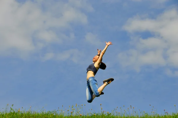 Красивая и счастливая девушка прыгает высоко на траве — стоковое фото