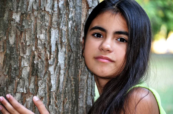 Retrato de uma linda menina de pé perto da árvore — Fotografia de Stock