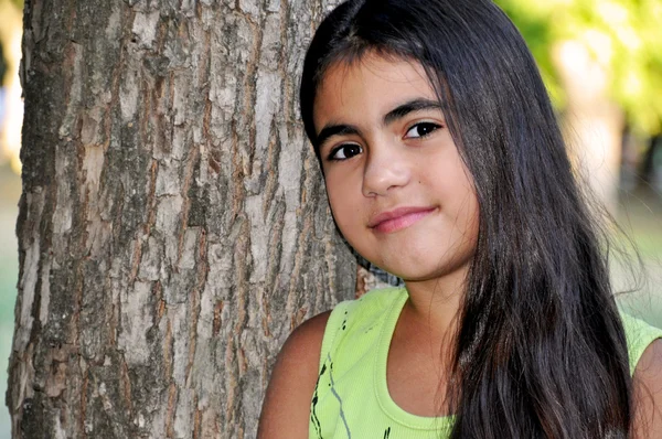 Retrato de una hermosa chica de pie cerca del árbol — Foto de Stock