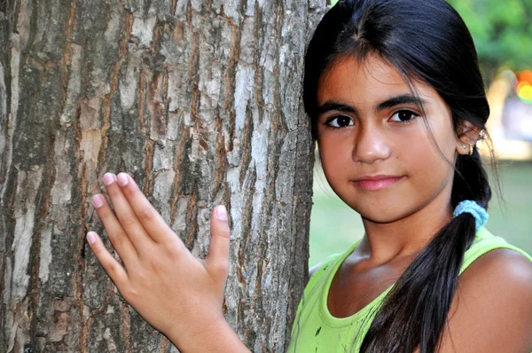 Retrato de uma linda menina de pé perto da árvore — Fotografia de Stock