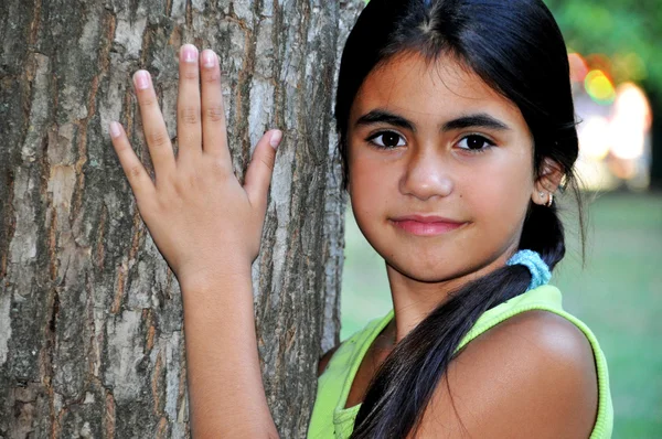 Retrato de uma linda menina de pé perto da árvore — Fotografia de Stock