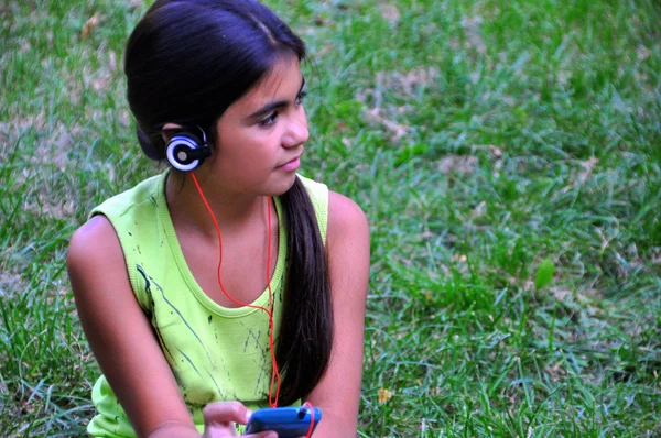 Ragazza con le cuffie Ascolta musica mentre ti rilassi nel parco . — Foto Stock