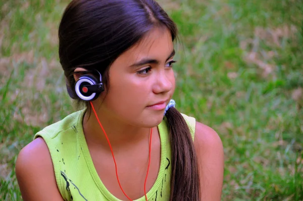 Dziewczyna z słuchawki słuchać muzyki podczas relaksu w parku. — Zdjęcie stockowe