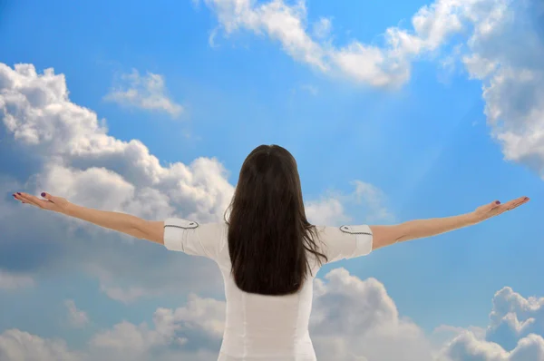 Деловая женщина с распростертыми к небу руками с облаками — стоковое фото