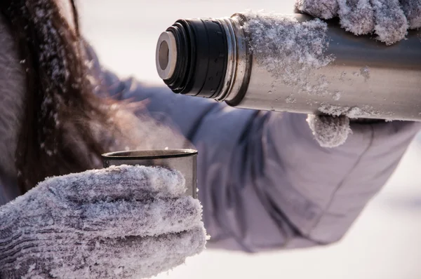 woman pours tea from a thermos winter