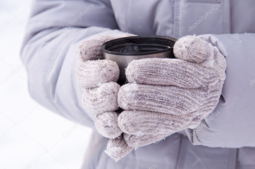 thermos cup in the hands of the girl in the winter