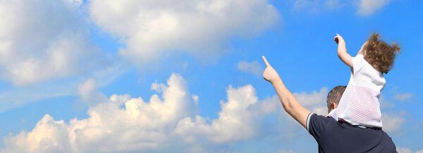 Отец с ребенком показывает что-то против неба
