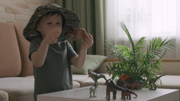 Boy Plays Dinosaur Figurines Table Little Explorer Hat Handheld Close — Stock Video