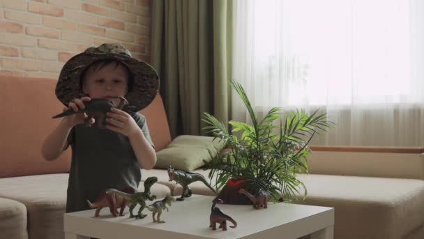 Niño Juega Con Figuras Dinosaurios Sobre Mesa Pequeño Explorador Sombrero — Vídeos de Stock