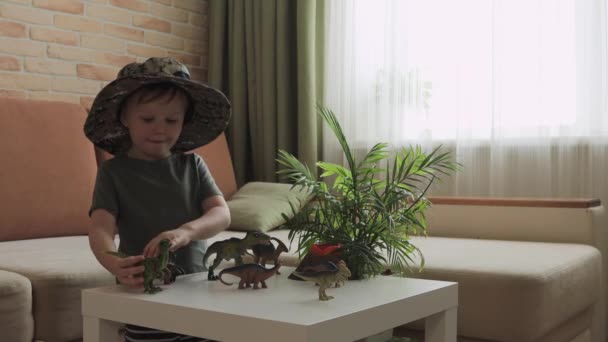 Niño Juega Con Figuras Dinosaurios Sobre Mesa Pequeño Explorador Sombrero — Vídeos de Stock