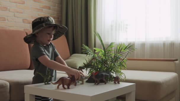 Niño Juega Con Figuras Dinosaurios Sobre Mesa Pequeño Explorador Sombrero — Vídeo de stock
