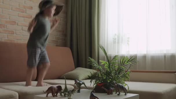 Een Jongen Die Bank Springt Met Dinosaurusfiguurtjes Tafel Kleine Ontdekkingsreiziger — Stockvideo