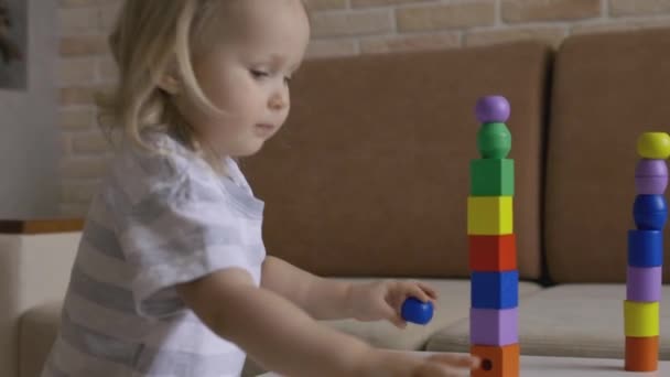 小さな女の子はテーブルの上で木製の幾何学的な数字を演奏 虹のキューブをソート 手を閉じてショット — ストック動画