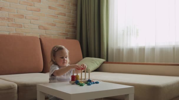 小さな女の子はテーブルの上で木製の教育ゲームをプレイ 虹の車輪を分類する — ストック動画