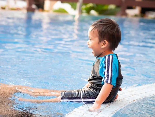 Yüzme havuzunun kenarında oturan küçük bir çocuk.