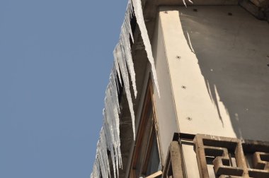 Çatıdan sarkan güzel buz saçakları. Şehirde kış güzeli. Donmuş su. Balkonda ve çatıda buz saçakları var..