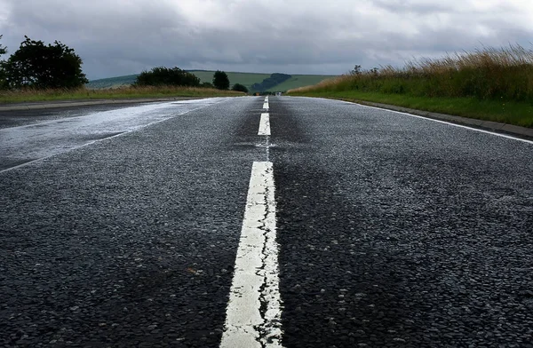 空旷的道路 白色的线在图像的中心 潮湿的柏油和多云的天空 图库图片