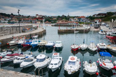 Cantabrian şehri Comillas 'ın ön cephesinde eğlence tekneleri ve arka planında şehir manzarası.