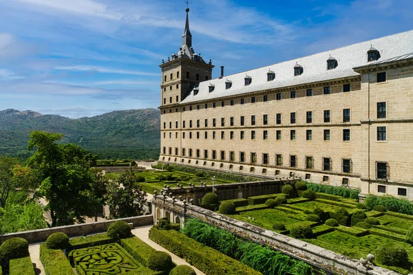 Madrid 'deki San Lorenzo de el Escorial manzarası, ön planda bahçeler ve açık beyaz bulutlu mavi gökyüzü..