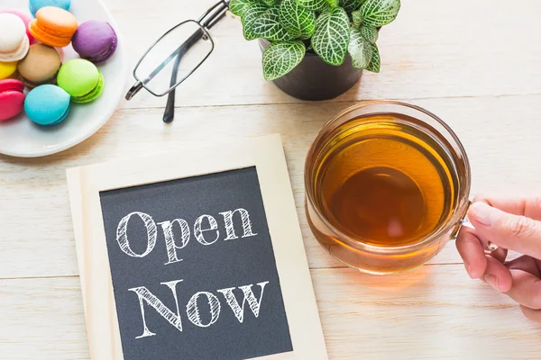 Concept Open now message on wood boards. Macaroons and glass Tea on table. Vintage tone. — Stock Photo, Image