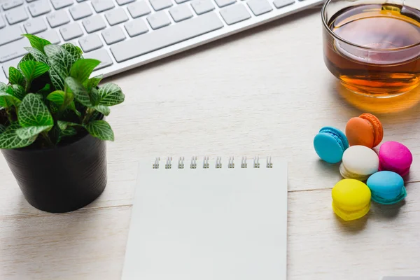 Un libro e una tastiera con una tazza di tè caldo, macaron sul tavolo. Può essere attribuito al tuo annuncio . — Foto Stock