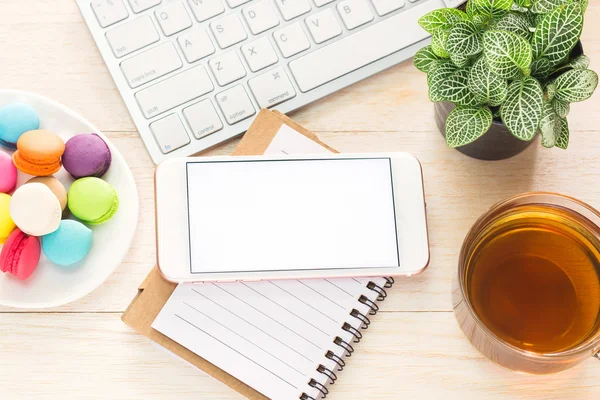 Area di lavoro ufficio con blocco note per tastiera caffè di tazza e smartphone su tavolo in legno . — Foto Stock