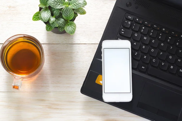 Bärbar dator, telefon och en kopp te på bordet. Kan vara monterade ad — Stockfoto