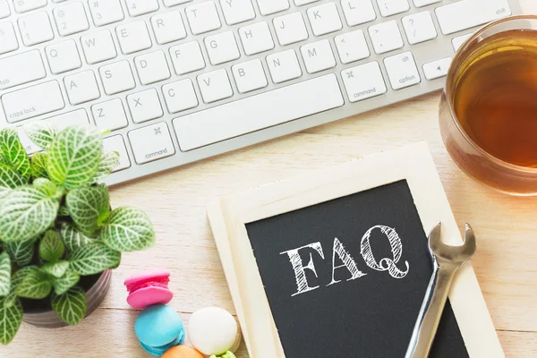 Konzept faq Botschaft auf Holzplatten. Makronen und Tee aus Glas auf dem Tisch. Vintage-Ton. — Stockfoto