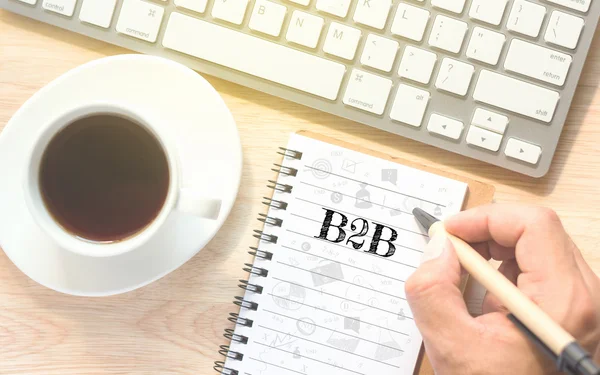 Escritura a mano en el mensaje del libro B2B (de empresa a empresa). Un teclado y una mesa de café de vidrio. . — Foto de Stock