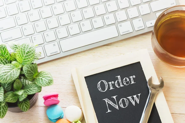 Kavram sipariş şimdi ahşap kurullarında mesaj. Macaroons ve cam çay tablo. Vintage sesi.