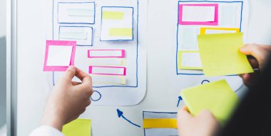 Mobil Uygulama Tasarımcıları akıllı telefon ve pembe kağıt üzerinde geliştirme, yaratıcı taslak planlama.