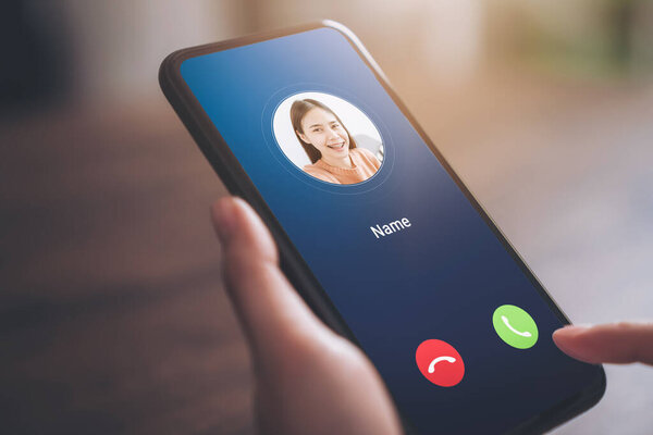 Рука держит смартфон и показывает экран входящего вызова от молодой девушки.