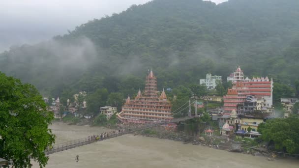 Nézd a Gangesz folyó Rishikesh és sokan sétáltak át a hídon. — Stock videók