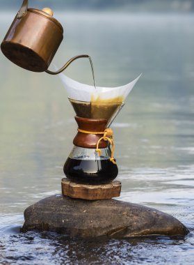 hand drip coffee  on the rocks at the river clipart