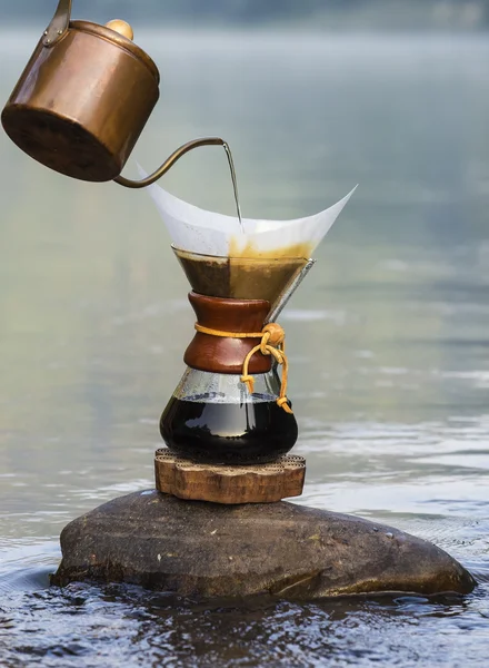 Hand tropft Kaffee auf die Felsen am Fluss — Stockfoto