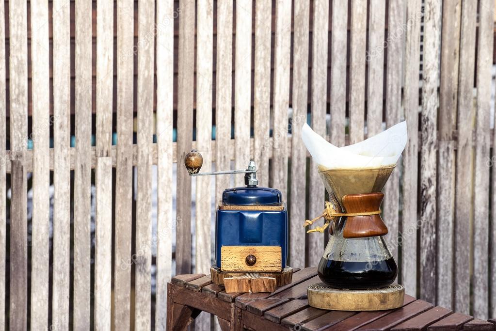 Metal coffee grinder and drip glass pitcher on old wooden backgr