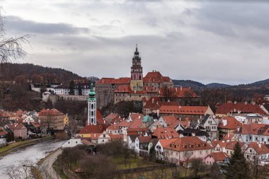 Aerial panorama view of Cesky Krumlov old town with the Cesky Krumlov castle and tower in background and Vltava river flowing around on a cloudy day, Czech Republic