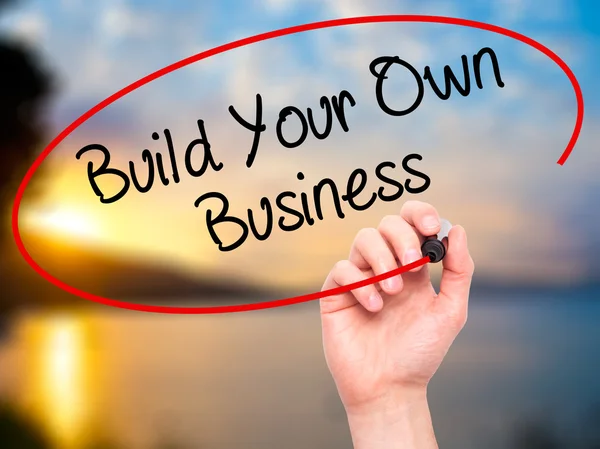 Man Hand writing Build Your Own Business with black marker on vi